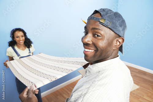 Photo: couple unrolling wallpaper in room back view couple unrolling wallpaper in room back view