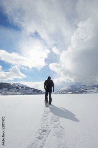 Photo: man walking in snowshoes through snow back view man walking in snowshoes through snow back view