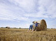 Two girls pushing bale of hay