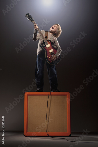 Photo: Boy playing electric guitar standing on speaker Boy playing electric guitar standing on speaker
