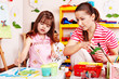 Child with teacher draw paints in play room.