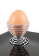 boiled egg in holder on black plate on white background