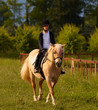 Ragazza bionda cavalca un pony Ragazza bionda cavalca un pony