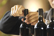 mani da uomo che stappano una bottiglia di vino rosso