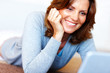 Happy mature woman using laptop while lying on floor