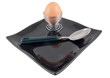 boiled egg and spoon on black plate on white background