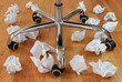 Papierknäuel auf Boden neben Stuhl