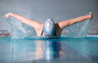 woman swims using the butterfly stroke in indoor pool