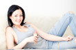 Frau in TShirt und Jean mit Eis liegt auf Couch