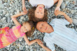 Happy family with girl lying on stony beach