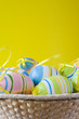 punnet with colorful easter eggs on yellow background