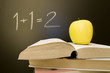 Book and apple, 1+1 written on chalkboard