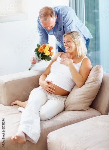 Photo: Mature man giving flowers to his pregnant wife Mature man giving flowers to his pregnant wife