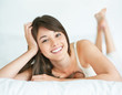 Happy young woman smiling while lying on bed
