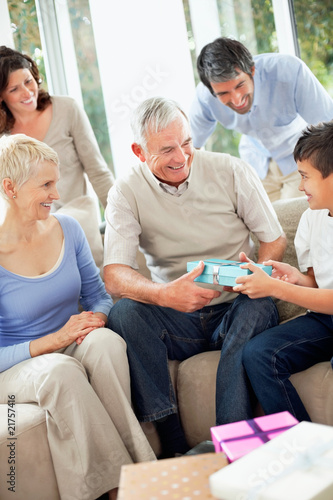 Foto: Family looking at happy grandfather gifting his grandson Family looking at happy grandfather gifting his grandson