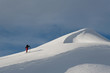 man hiking on mountain peak with skies