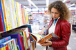 girl thoughtfully considers children's book in bookshop.