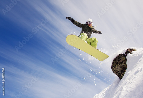 Photo: Snowboarder jumping through air with blue sky in background Snowboarder jumping through air with blue sky in background