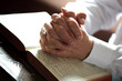 Praying hands on an open bible