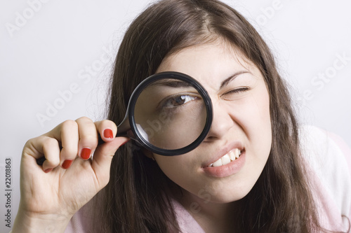 pretty young woman looking through magnifying