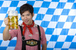 Glücklicher Chinesischer Mann mit Lederhose hält Oktoberfest Maß