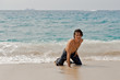 Athletic young man on the beach in the ocean waves.