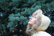 The girl looks at the green spruce