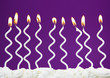 White birthday candles on lilac background
