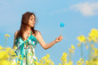 woman on rape(canola) field with hand mill over blue sky