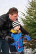 Man cutting a Christmas Tree with his son
