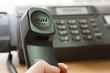 The female hand holds a tube of black office phone-fax