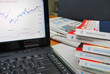 Financial books with graph on laptop