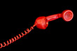 Red telephone receiver isolated on a black background