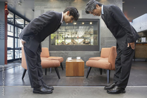 Photo: Two businessmen bowing to each other in cafe Two businessmen bowing to each other in cafe