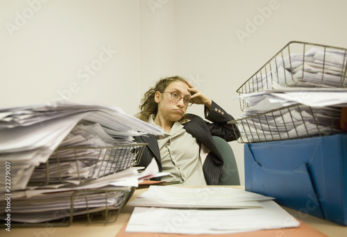 Photo: Hispanic businesswoman looking at piles of paperwork Hispanic businesswoman looking at piles of paperwork