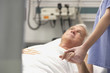 Doctor holding male patient's hand in hospital room