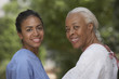 African female nurse and senior female patient smiling outdoors