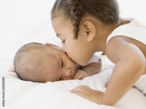Photo: African girl kissing newborn baby sibling African girl kissing newborn baby sibling