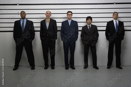 Photo: Multi-ethnic businessmen in police line up Multi-ethnic businessmen in police line up