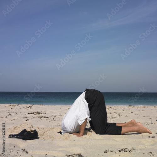 Photo: Hispanic businessman with head in sand Hispanic businessman with head in sand