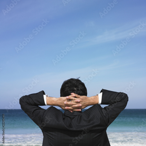 Photo: Hispanic businessman looking out over ocean Hispanic businessman looking out over ocean