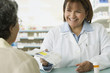 Hispanic female pharmacist handing medication to customer