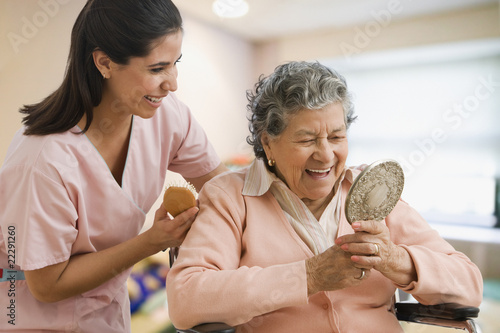 Photo: Hispanic nurse helping senior woman with hair Hispanic nurse helping senior woman with hair