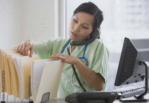 Photo: Asian female doctor talking on telephone Asian female doctor talking on telephone