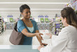 African woman picking up prescription at pharmacy