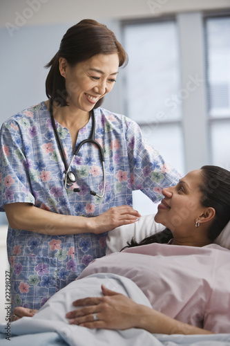 Photo: Asian nurse smiling at Hispanic female patient Asian nurse smiling at Hispanic female patient