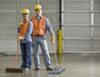 Multi-ethnic warehouse workers holding brooms