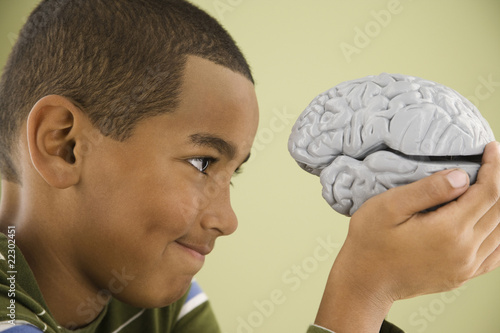 Photo: Mixed Race boy looking at model brain Mixed Race boy looking at model brain