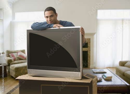 Photo: Hispanic man leaning on new television Hispanic man leaning on new television