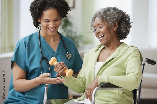 Foto: African home nurse helping woman in wheelchair with hand weight African home nurse helping woman in wheelchair with hand weight